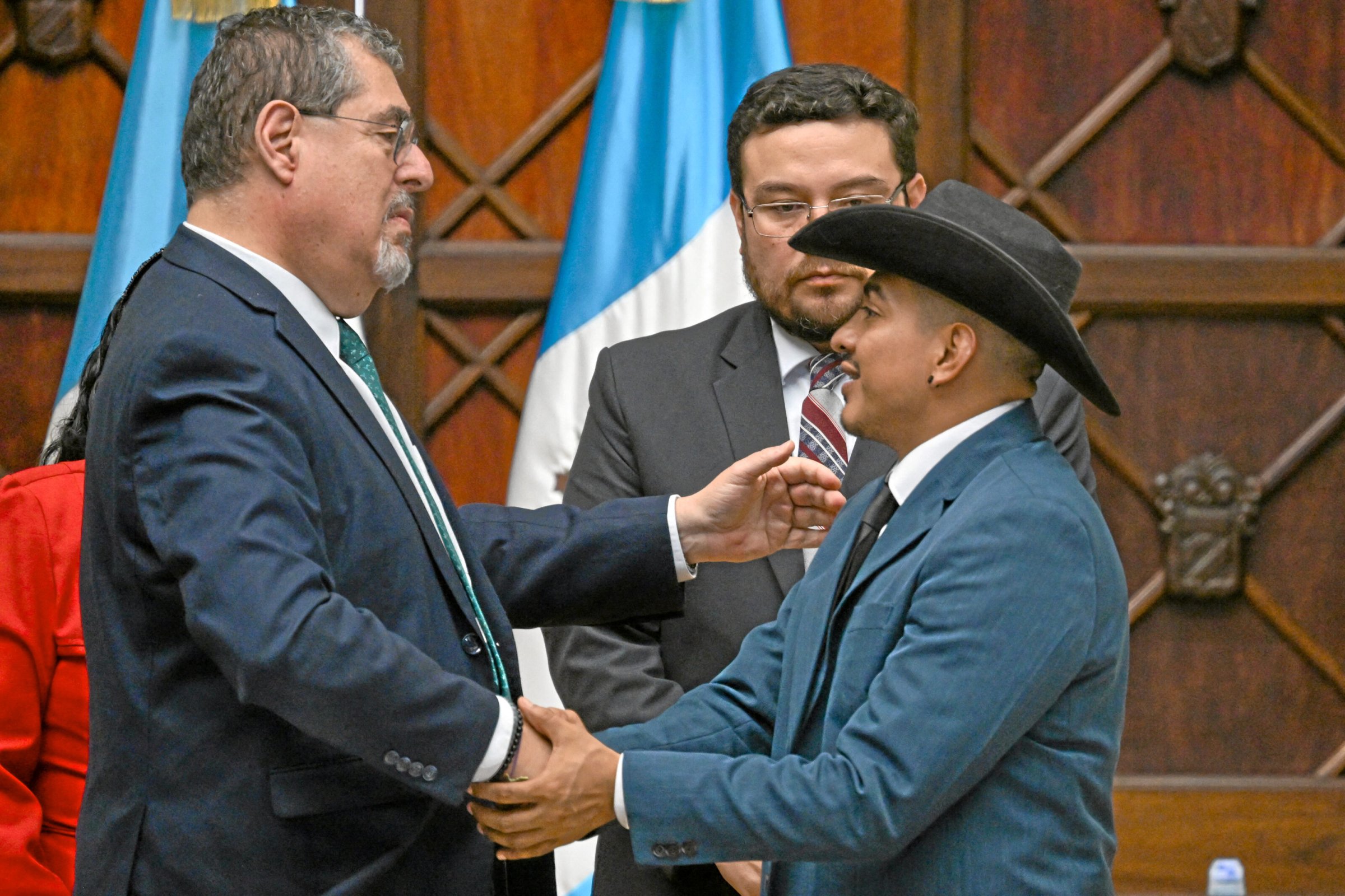 Guatemalas Präsident Bernardo Arévalo (l.) schüttelt dem zwangsadoptierten Osmín Tobar bei der Zeremonie die Hand.