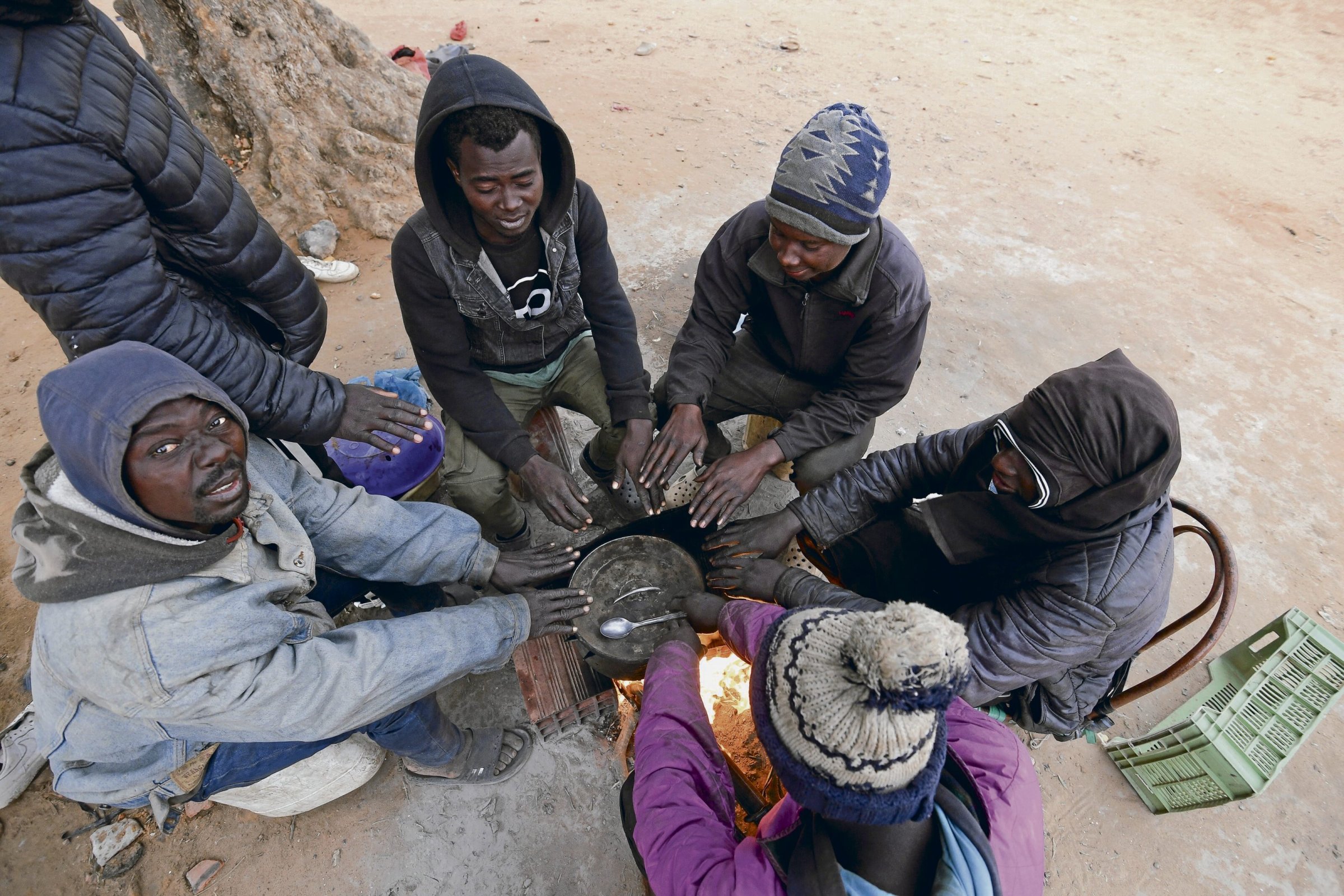 Migranten aus Subsahara-Afrika versammeln sich um ein Feuer in einem Lager in Jebeniana im tunesischen Gouvernement Sfax.