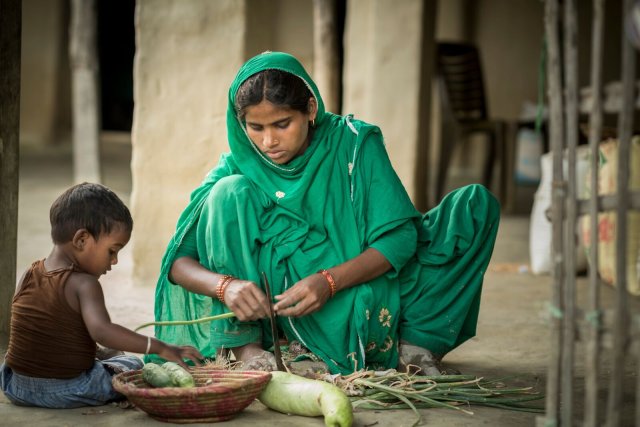 Eine nepalesische Frau mit ihrem Kind beim Vorbereiten von geerntetem Gemüse. Die Welthungerhilfe liefert Unterstützung mit Hilfe zur Selbsthilfe.