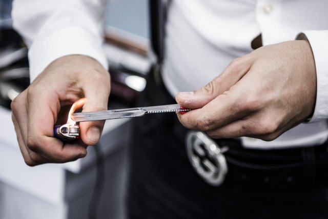 Sieht gefährlich aus, aber sorgt für Sicherheit: Berliner Barbier desinfiziert sein Rasiermesser mit Feuerzeug und Alkohol.