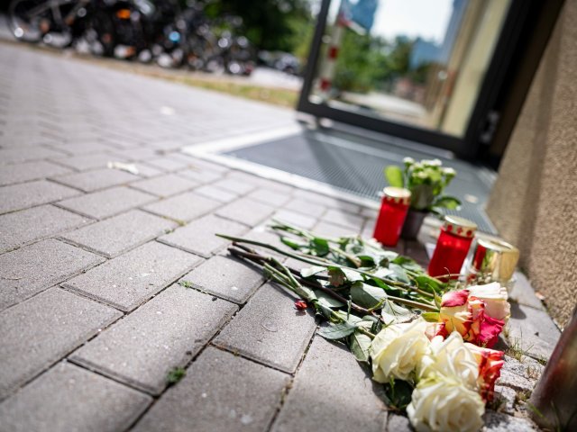 Blumen und Kerzen liegen vor dem Haus in Berlin-Friedrichsfelde, in dem am Freitagabend eine 28-Jährige erstochen wurde.