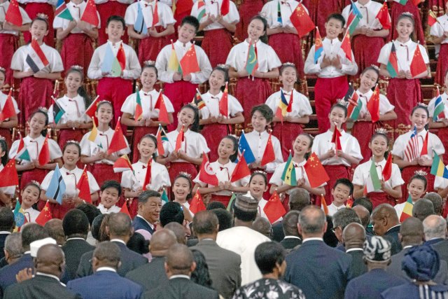 Chinas Präsident Xi Jinping (unten, l.) steht während eines Empfangs auf dem Forum für chinesisch-afrikanische Zusammenarbeit (FOCAC) in der Großen Halle des Volkes gemeinsam mit Staatsoberhäuptern afrikanischer Länder vor einer Gruppe von Kindern, die afrikanische und chinesische Flaggen halten und singen.