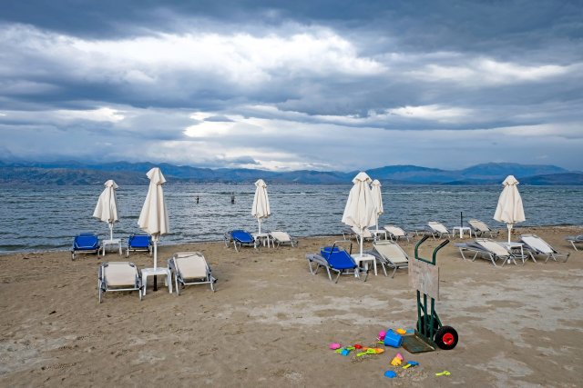 Sonnenschirme, Liegen und vergessenes Kinderspielzeug am Kalamaki Strand auf Korfu werden am Saisonende im Winterlager verstaut.