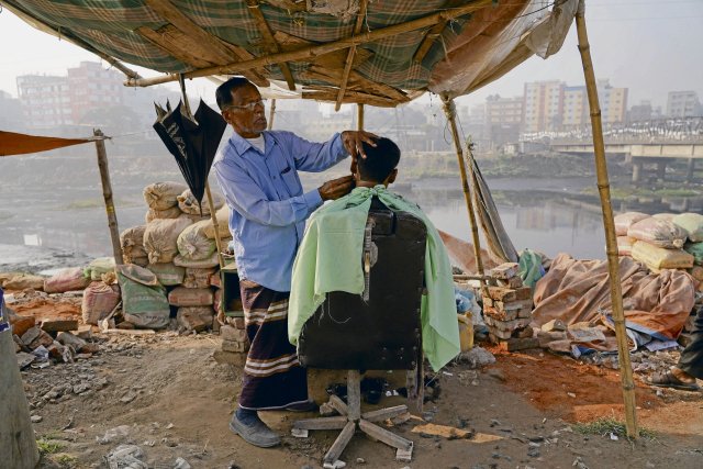 Improvisierter Friseur in Dhaka: Die Armut grassiert in Bangladesch – maßgeblich hervorgerufen durch eine neoliberale Wirtschaftspolitik und immer häufiger auftretende Umweltkatastrophen.