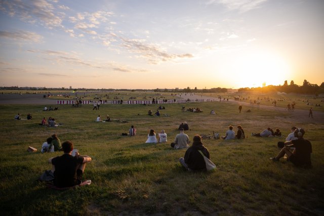 Menschen sitzen auf dem Tempelhofer Feld. Die Grünflächen könnte für eine Randbebauung genutzt werden.