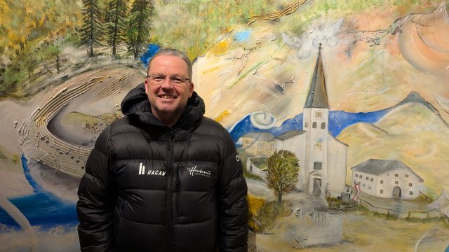 Hotelchef Albert Ebner jr. vor einem Gemälde, das die Ortschaft Hintersee zeigt